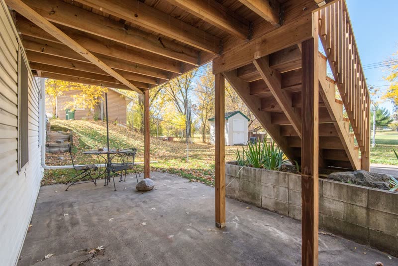 Concrete patio under a raised wood deck in a back yard